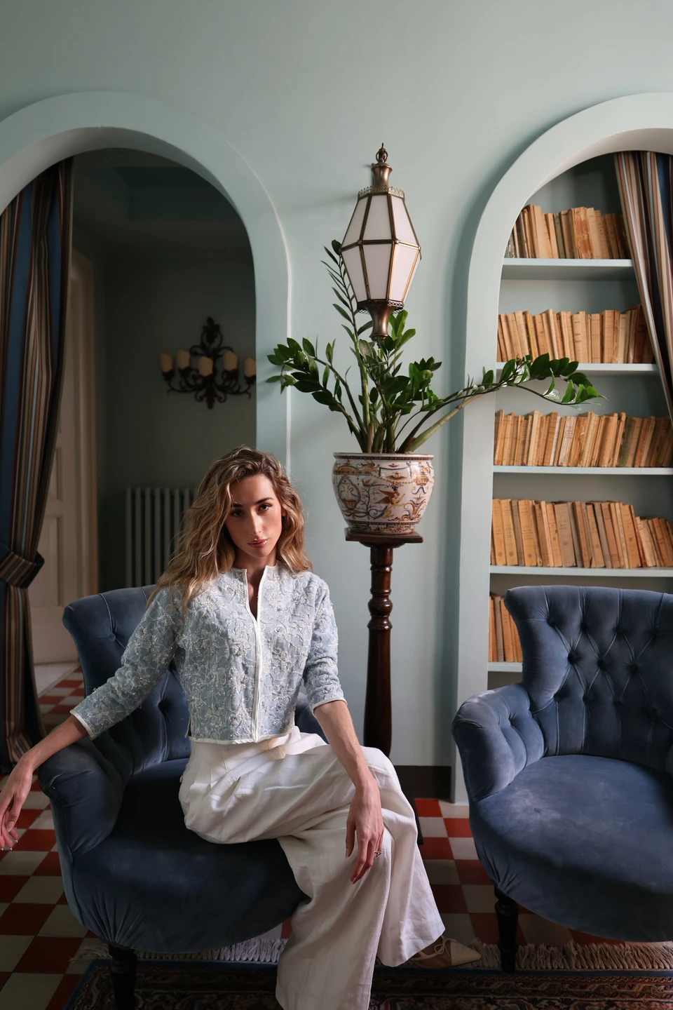 Taylor, founder of Fabulous, seated in a blue armchair beside a bookcase.